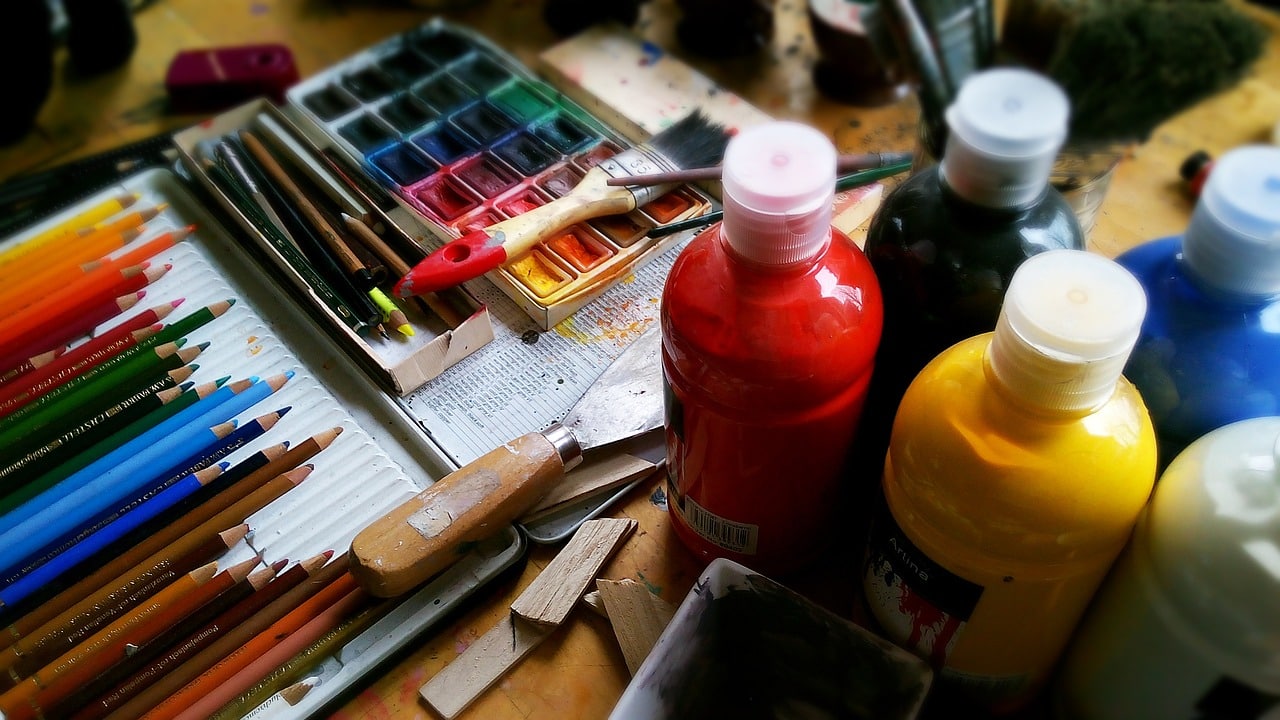 Botes y lápices de pintura de colores sobre mesa para artes plásticas